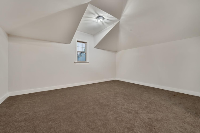 additional living space with lofted ceiling and dark colored carpet