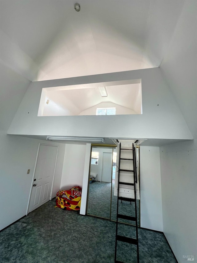 additional living space featuring dark colored carpet and lofted ceiling