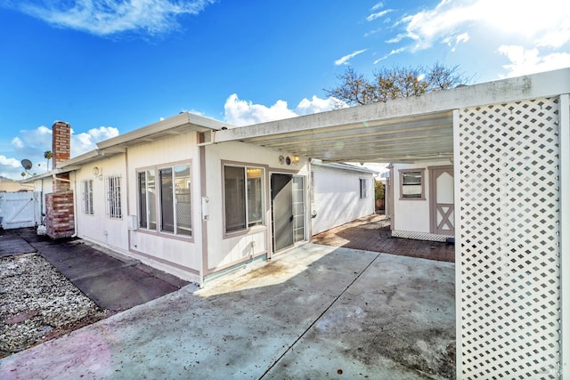 rear view of property with a carport and a patio area