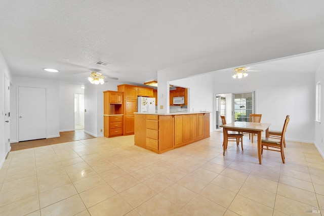 kitchen featuring kitchen peninsula, white appliances, ceiling fan, and light tile patterned flooring