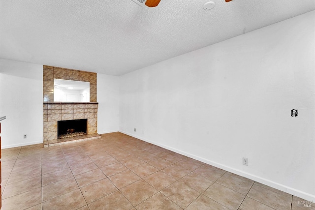 unfurnished living room with light tile patterned floors, a textured ceiling, and a tiled fireplace