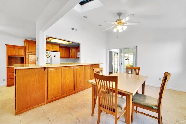 tiled dining room featuring a skylight and ceiling fan