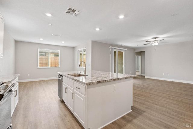 kitchen with appliances with stainless steel finishes, a kitchen island with sink, sink, light hardwood / wood-style flooring, and white cabinets