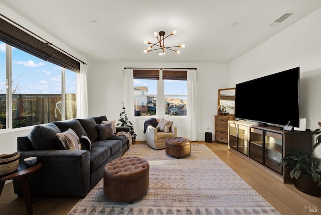 living room with a chandelier, light hardwood / wood-style flooring, and a healthy amount of sunlight