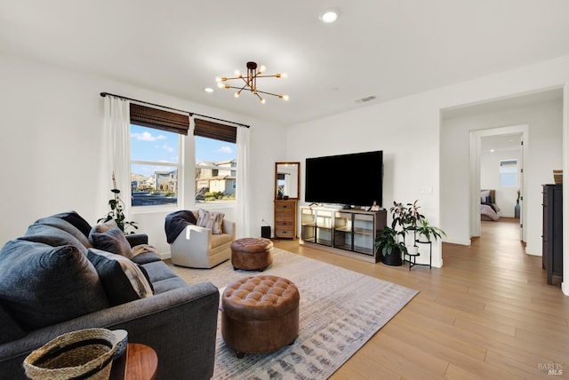 living room with light wood-type flooring and an inviting chandelier