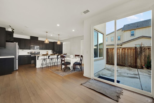 interior space featuring a center island, hanging light fixtures, light hardwood / wood-style flooring, a breakfast bar area, and appliances with stainless steel finishes