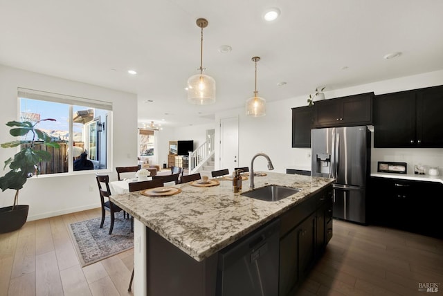 kitchen with stainless steel appliances, light hardwood / wood-style flooring, a kitchen island with sink, and sink