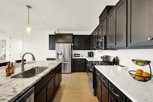 kitchen with sink, appliances with stainless steel finishes, decorative light fixtures, light hardwood / wood-style floors, and dark brown cabinetry