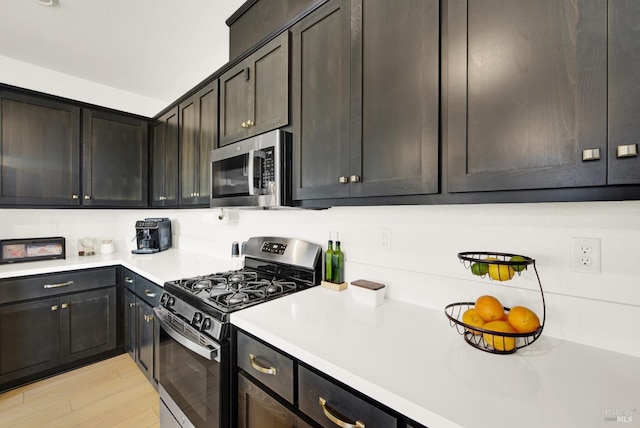 kitchen with appliances with stainless steel finishes, dark brown cabinetry, and light hardwood / wood-style floors