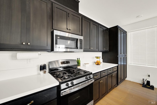 kitchen with dark brown cabinets, light wood-type flooring, and appliances with stainless steel finishes