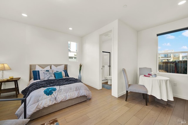 bedroom with ensuite bath and light hardwood / wood-style flooring