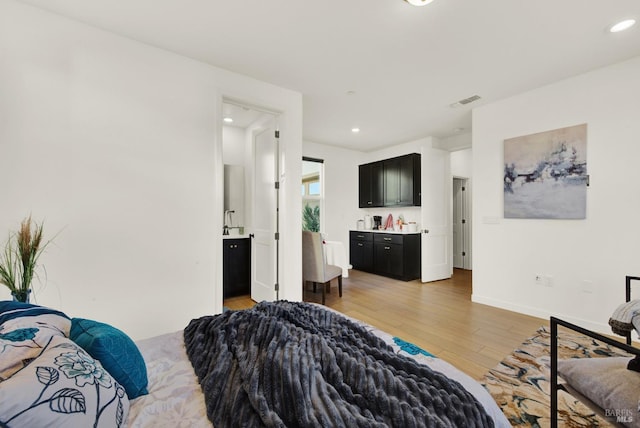 bedroom with light hardwood / wood-style floors and ensuite bath