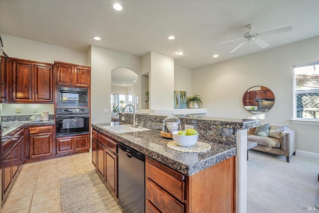 kitchen featuring ceiling fan, black appliances, sink, a kitchen island with sink, and light carpet