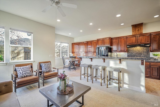 carpeted living room featuring ceiling fan and sink