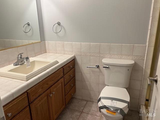 bathroom featuring tile patterned flooring, vanity, and tile walls