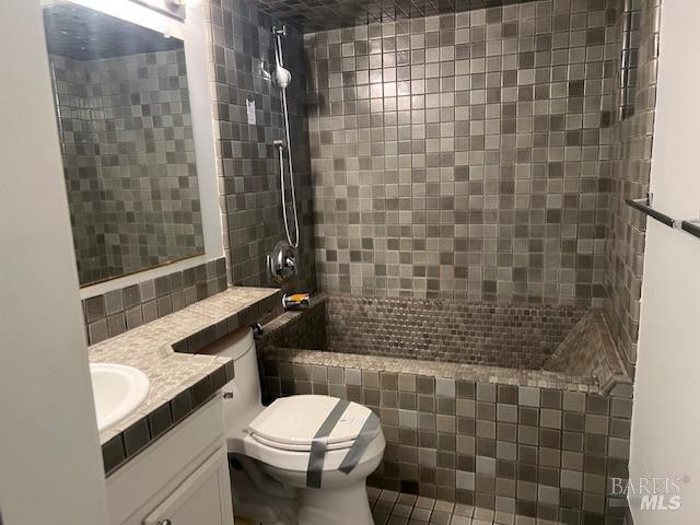 bathroom with vanity, toilet, and a tile shower