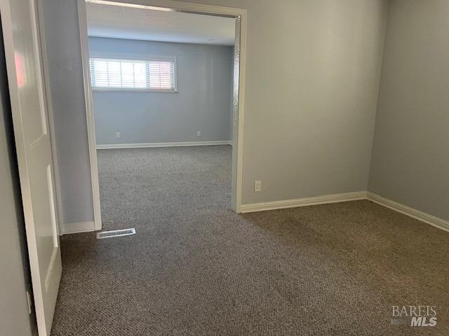 empty room with baseboards, carpet flooring, and visible vents