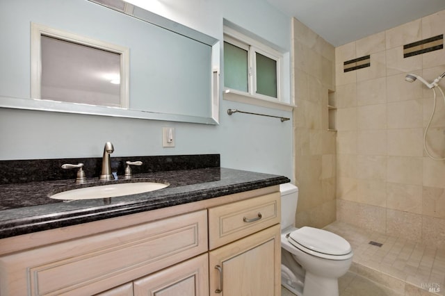 bathroom featuring a tile shower, vanity, toilet, and tile patterned floors