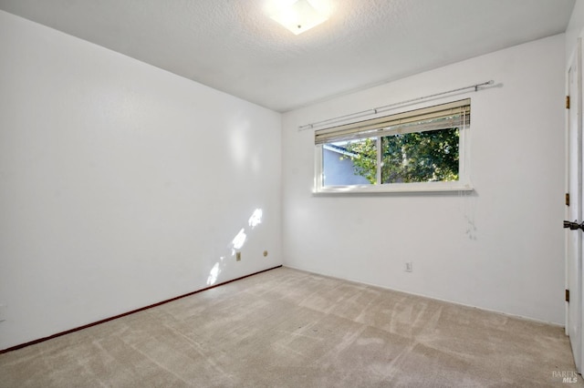 carpeted empty room featuring a textured ceiling