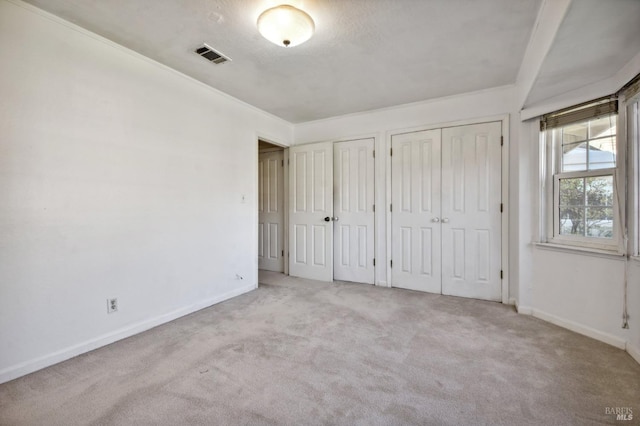 unfurnished bedroom featuring light colored carpet and two closets