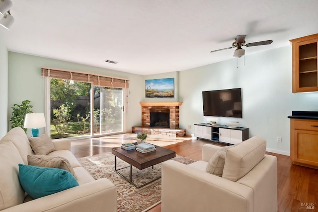 living room with a fireplace, light hardwood / wood-style floors, and ceiling fan