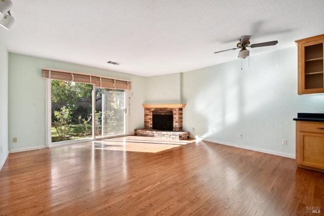 unfurnished living room featuring a fireplace, ceiling fan, and hardwood / wood-style floors