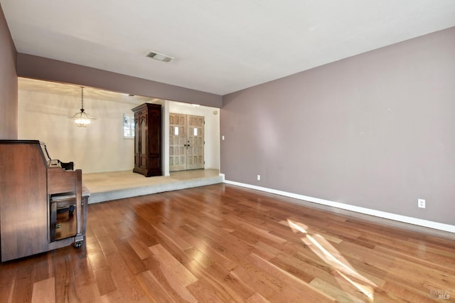 unfurnished living room featuring wood-type flooring and an inviting chandelier