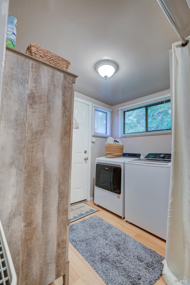 laundry room with light wood-type flooring, washing machine and dryer, and laundry area