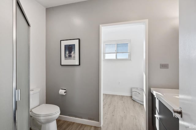 bathroom featuring hardwood / wood-style flooring, vanity, toilet, and a shower with shower door