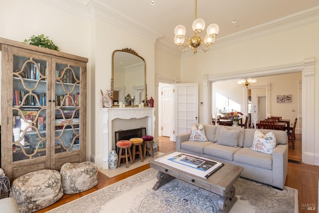 living room with a chandelier, hardwood / wood-style floors, a towering ceiling, and ornamental molding