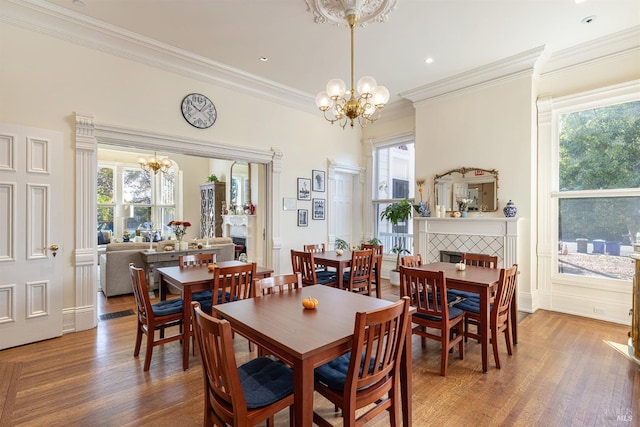 dining area with a tile fireplace, hardwood / wood-style floors, an inviting chandelier, and a wealth of natural light