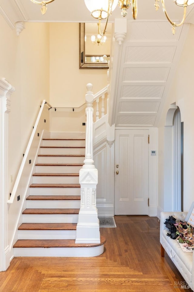 stairway featuring a notable chandelier and wood-type flooring