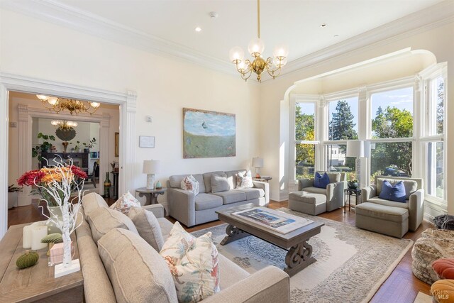 living room with a chandelier, wood-type flooring, ornamental molding, and a healthy amount of sunlight