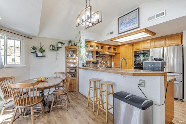 kitchen with freestanding refrigerator, visible vents, vaulted ceiling, and under cabinet range hood