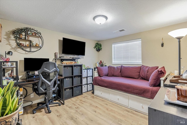 home office with a textured ceiling, wood finished floors, and visible vents