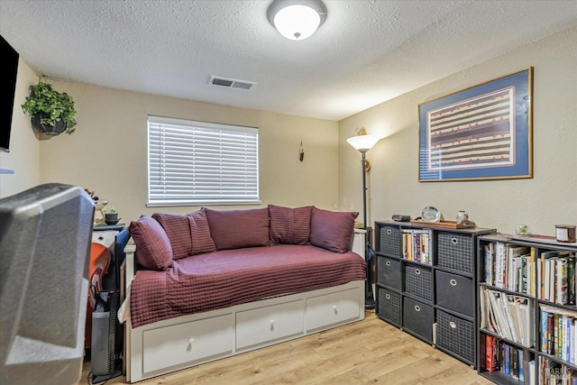 bedroom featuring visible vents, a textured ceiling, and wood finished floors