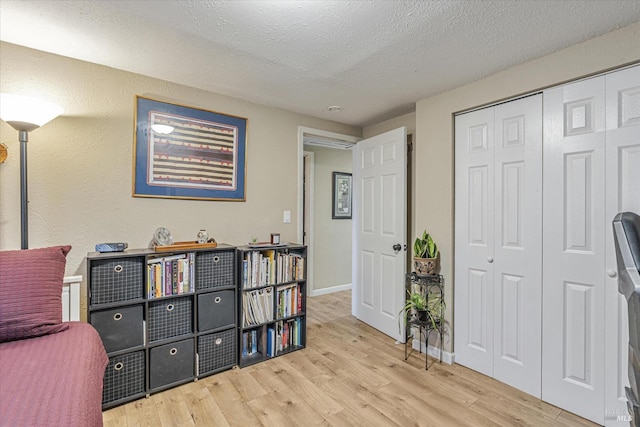 bedroom featuring a textured ceiling, a closet, baseboards, and wood finished floors