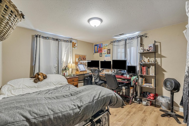 bedroom featuring a textured ceiling, wood finished floors, and visible vents