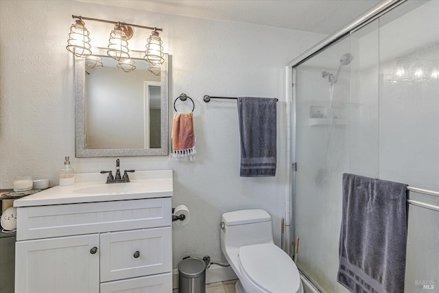 bathroom with a textured wall, a shower stall, toilet, and vanity