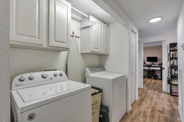 laundry area with cabinet space, light wood-style flooring, and washer and dryer