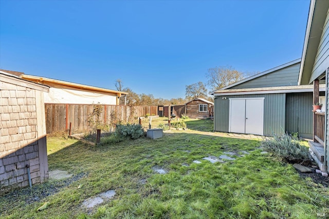 view of yard with fence, an outdoor structure, and a storage unit