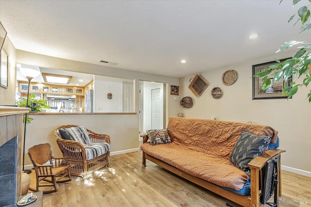 living area featuring a fireplace, recessed lighting, visible vents, baseboards, and hardwood / wood-style flooring