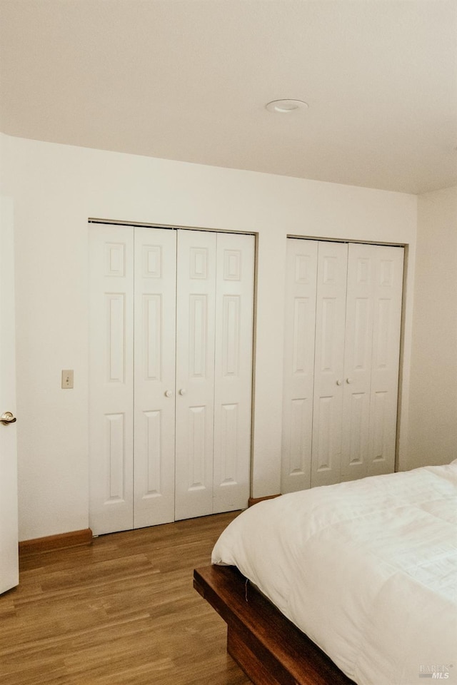 bedroom with multiple closets and hardwood / wood-style flooring