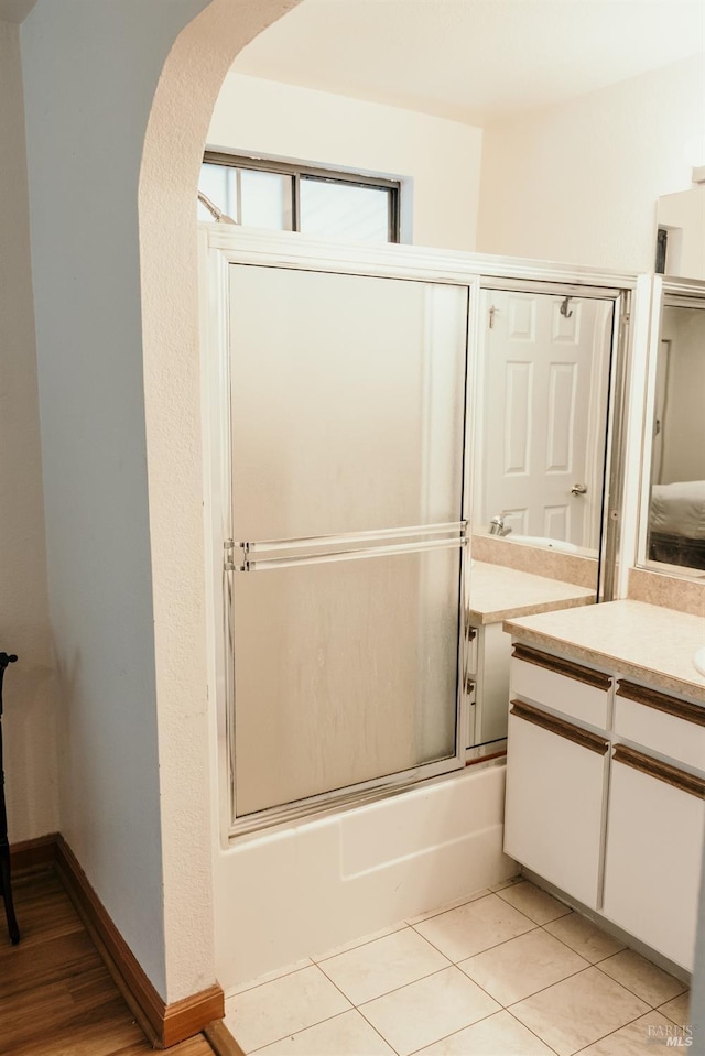 bathroom with tile patterned flooring, vanity, and bath / shower combo with glass door