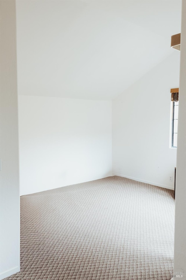 empty room featuring carpet and vaulted ceiling