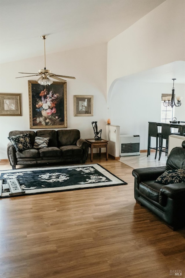 living room with ceiling fan with notable chandelier, wood-type flooring, and vaulted ceiling