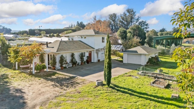 view of front of home with a garage, a front lawn, and an outdoor structure