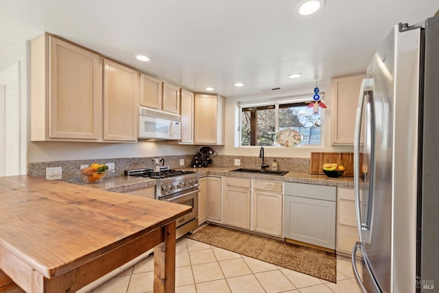 kitchen with wood counters, light tile patterned floors, sink, and appliances with stainless steel finishes