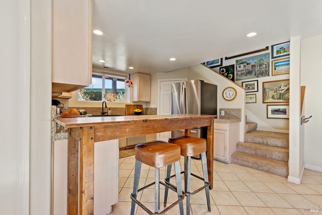 kitchen featuring kitchen peninsula, light tile patterned floors, a breakfast bar area, and sink