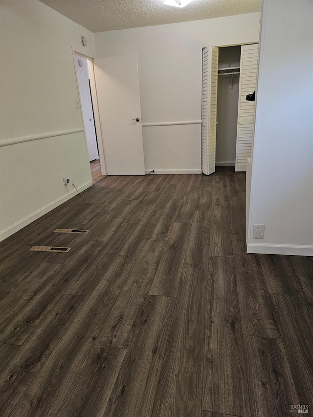 unfurnished bedroom with dark hardwood / wood-style flooring, a textured ceiling, and a closet